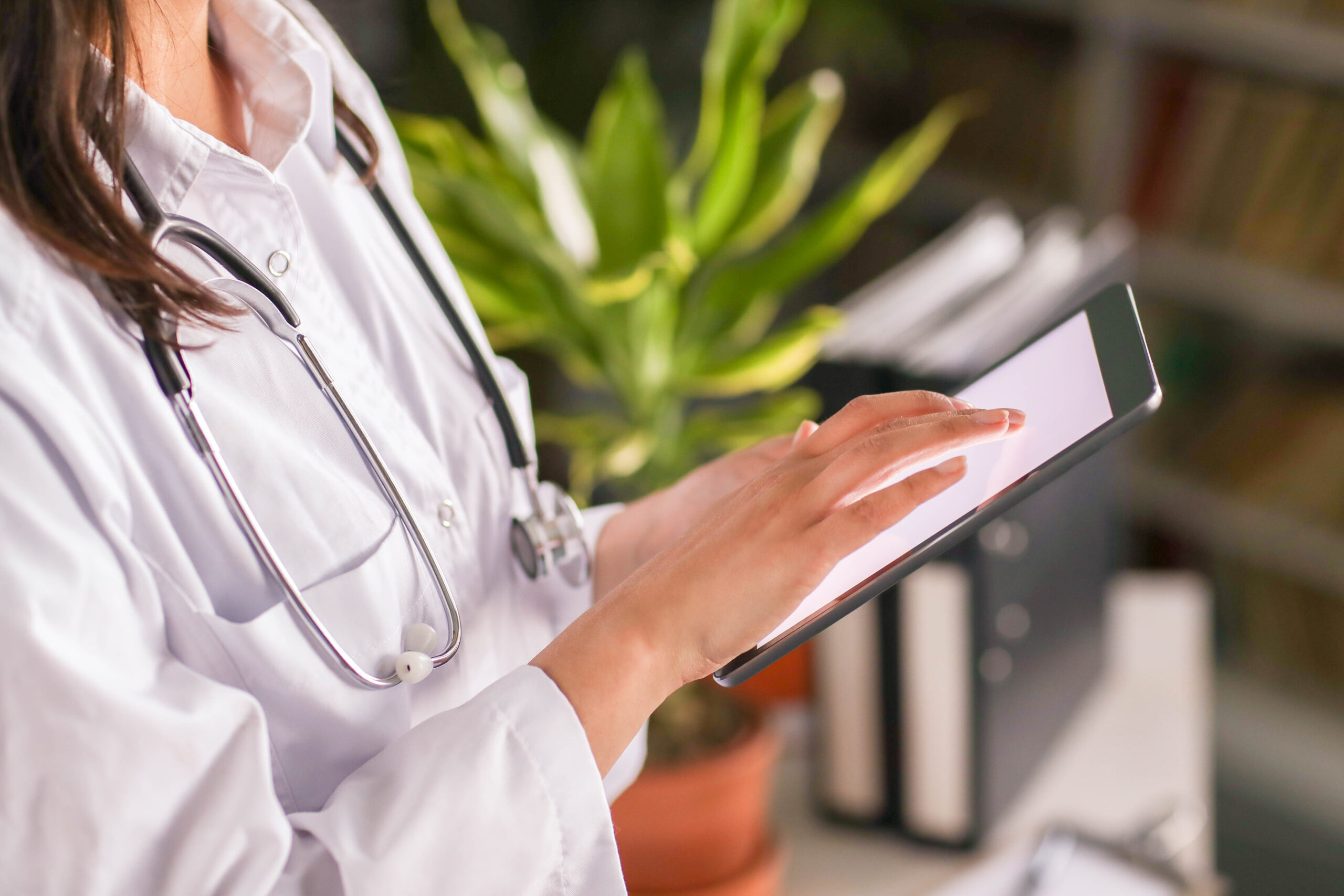 Docteur tenant une tablette tactile pour éditer un bilan de kinésithérapie d'un de ses patients grâce à la solution EMNIA
